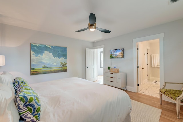 bedroom featuring visible vents, ensuite bathroom, baseboards, ceiling fan, and light wood finished floors