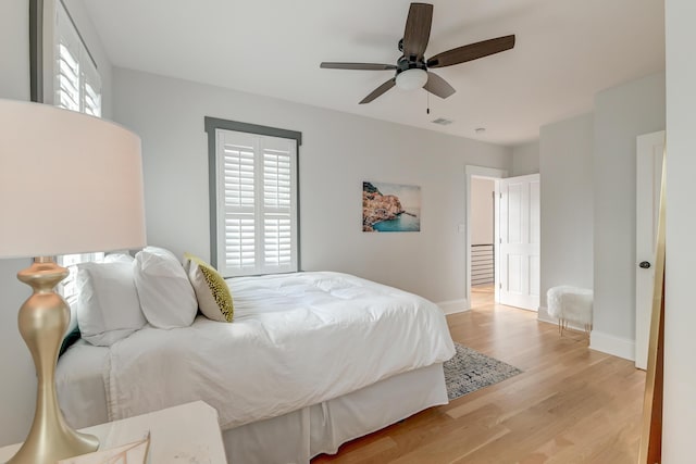 bedroom featuring baseboards, visible vents, ceiling fan, and light wood-style floors