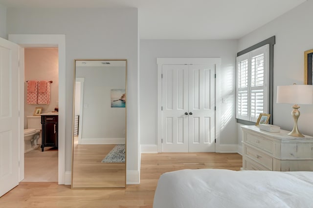 bedroom with a closet, light wood finished floors, and baseboards