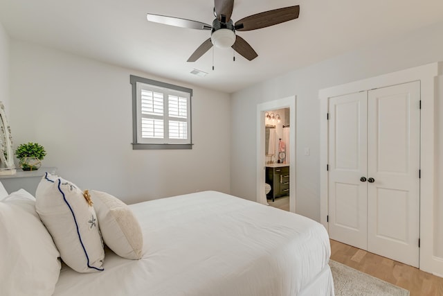 bedroom featuring ceiling fan, ensuite bath, light wood-style floors, visible vents, and a closet