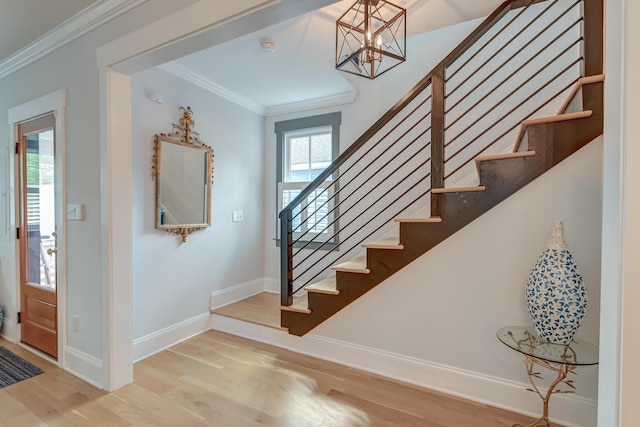 staircase with crown molding, baseboards, an inviting chandelier, and wood finished floors