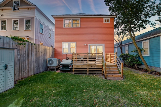 back of house at dusk featuring ac unit, a wooden deck, a yard, and fence