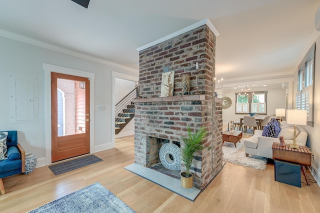living room featuring crown molding, stairs, wood finished floors, baseboards, and a notable chandelier