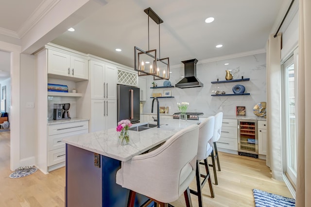 kitchen with tasteful backsplash, open shelves, freestanding refrigerator, beverage cooler, and wall chimney exhaust hood