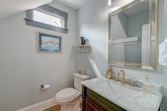 half bathroom featuring vanity, baseboards, toilet, and wood finished floors