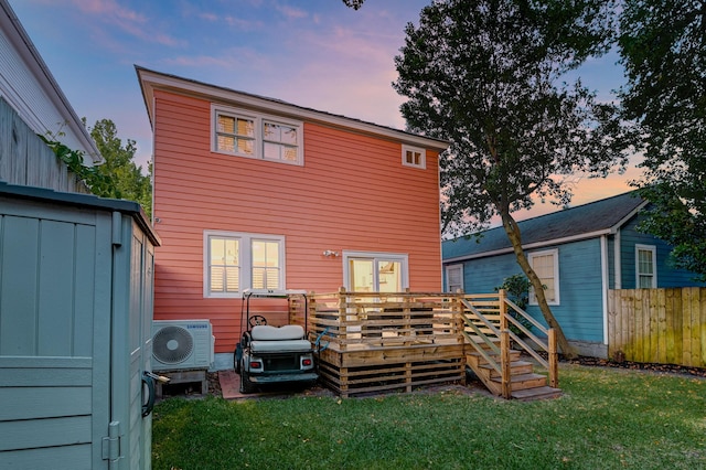 rear view of house featuring an outdoor structure, a wooden deck, fence, a lawn, and ac unit