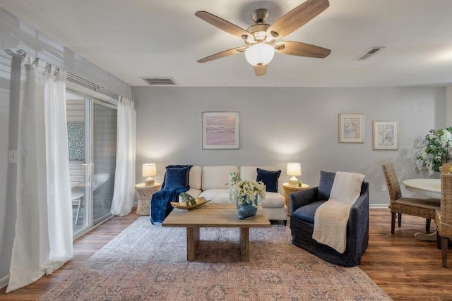 living area with a ceiling fan, visible vents, and wood finished floors