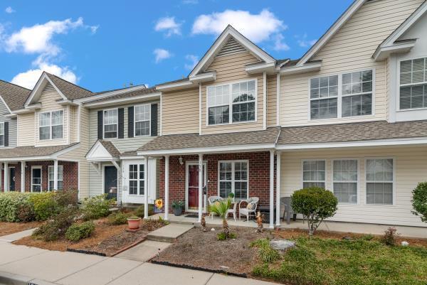 townhome / multi-family property with covered porch, a shingled roof, and brick siding