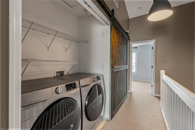 clothes washing area with light carpet, laundry area, a barn door, baseboards, and washing machine and clothes dryer