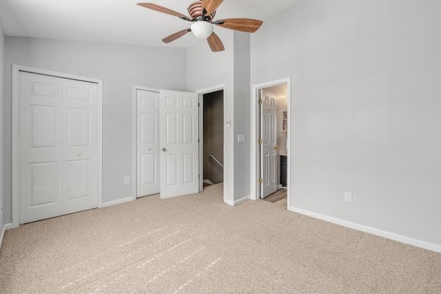 unfurnished bedroom with lofted ceiling, baseboards, multiple closets, and carpet flooring