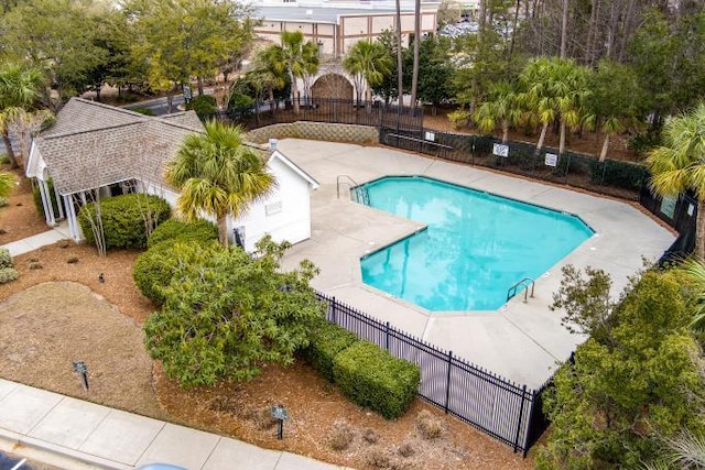 community pool with a patio area and fence