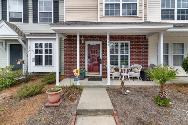 doorway to property featuring a porch and brick siding