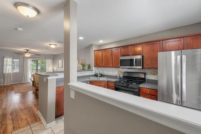 kitchen featuring a peninsula, backsplash, stainless steel appliances, and a sink