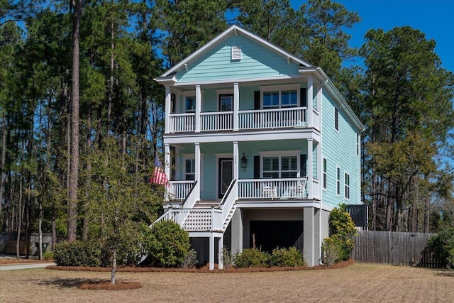 view of front facade featuring a balcony, covered porch, stairs, and fence