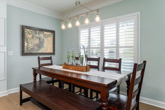 dining space featuring baseboards, wood finished floors, and crown molding