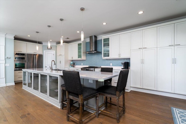 kitchen featuring wall chimney range hood, tasteful backsplash, appliances with stainless steel finishes, and dark wood finished floors