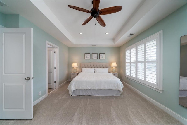 carpeted bedroom with a tray ceiling, recessed lighting, visible vents, and baseboards