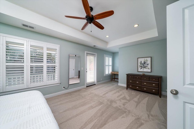 carpeted bedroom with ceiling fan, recessed lighting, visible vents, baseboards, and a tray ceiling