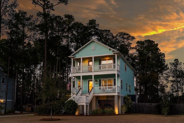 view of front of home featuring a balcony, stairs, fence, and a porch