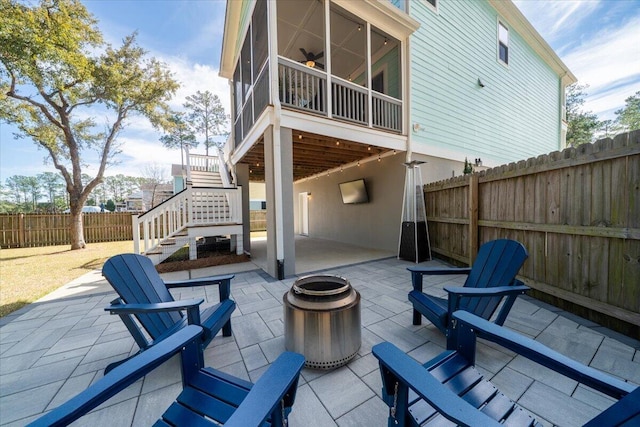 view of patio with a sunroom, an outdoor fire pit, stairs, and fence