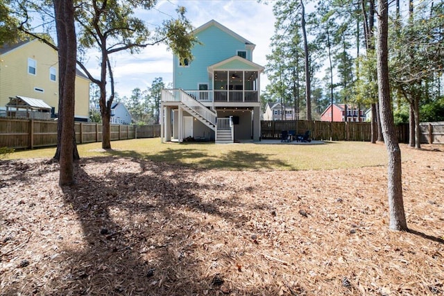 back of house featuring a lawn, a patio, a sunroom, a fenced backyard, and stairway