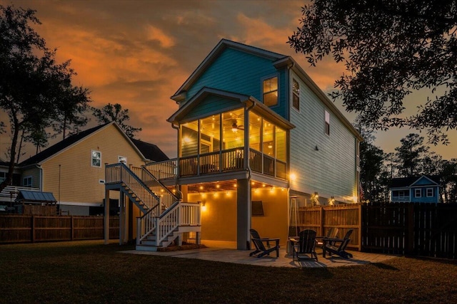 rear view of property with a yard, stairway, a sunroom, a patio area, and fence