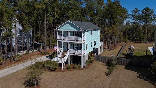 back of property featuring a porch, driveway, a balcony, and fence