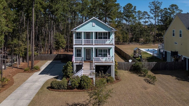 view of front facade featuring stairway, covered porch, fence, and a balcony