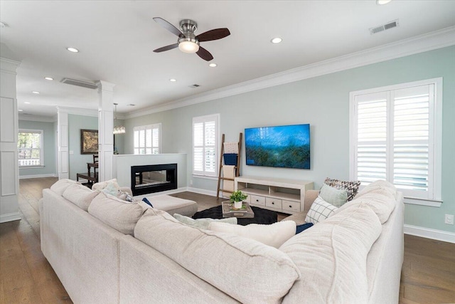 living area with ornamental molding, dark wood-style flooring, visible vents, and decorative columns