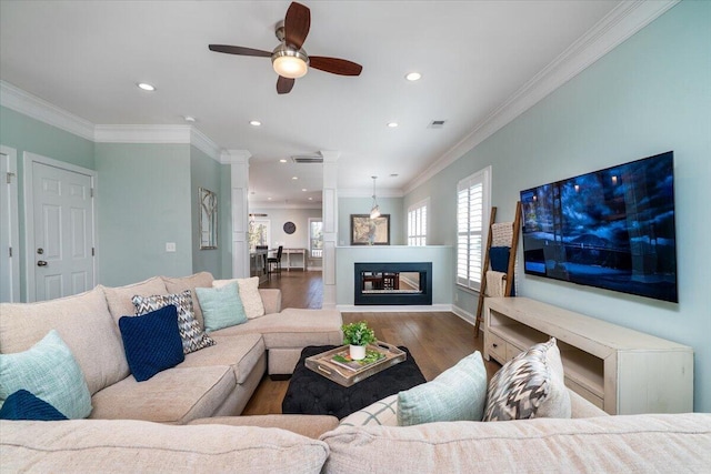 living area featuring ornamental molding, a glass covered fireplace, wood finished floors, and recessed lighting