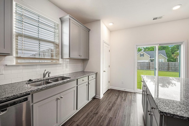 kitchen with dishwasher, a sink, dark wood-style floors, gray cabinets, and backsplash