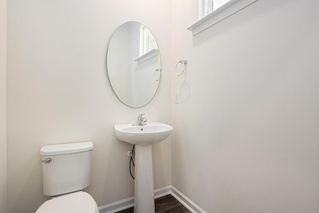 bathroom featuring toilet, baseboards, wood finished floors, and plenty of natural light