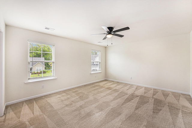 spare room featuring plenty of natural light, light carpet, and baseboards