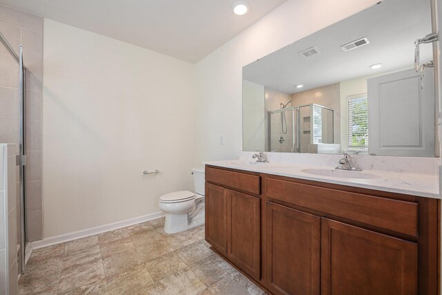 full bath featuring toilet, a stall shower, baseboards, and double vanity