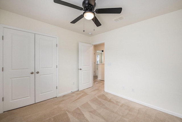 unfurnished bedroom with light carpet, baseboards, a closet, and a ceiling fan
