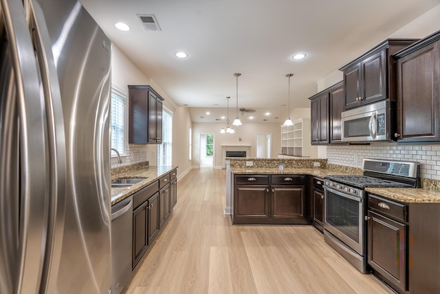 kitchen with appliances with stainless steel finishes, a sink, dark brown cabinetry, and recessed lighting