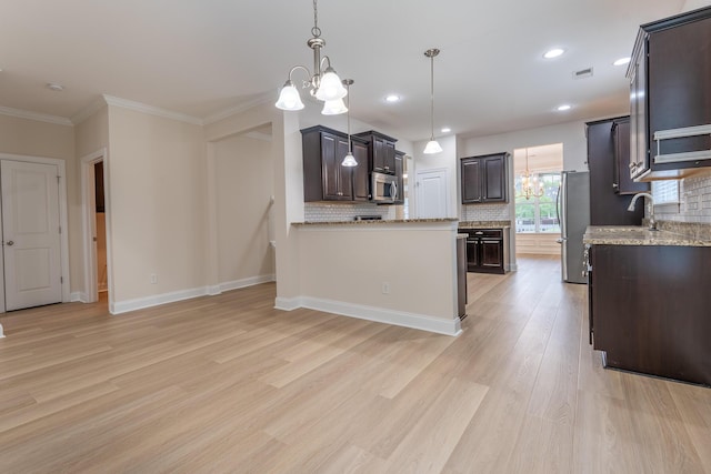 kitchen with stainless steel appliances, a chandelier, light wood finished floors, dark brown cabinetry, and decorative backsplash