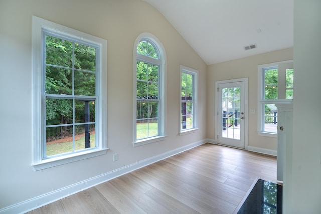 empty room featuring vaulted ceiling, light wood-style flooring, and baseboards