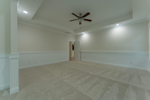 carpeted empty room featuring a tray ceiling, ceiling fan, ornamental molding, a wainscoted wall, and recessed lighting