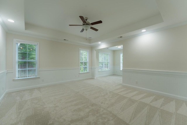 carpeted empty room featuring a raised ceiling, a wainscoted wall, ornamental molding, ceiling fan, and recessed lighting