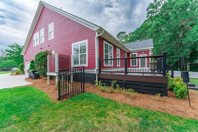 view of home's exterior with a wooden deck, concrete driveway, and a lawn