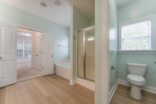 bathroom with wood finished floors, a shower stall, a garden tub, and healthy amount of natural light