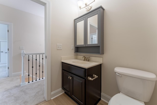 half bathroom with toilet, vanity, and baseboards