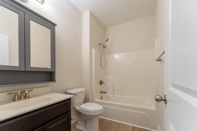 bathroom with toilet, wood finished floors, vanity, and shower / washtub combination