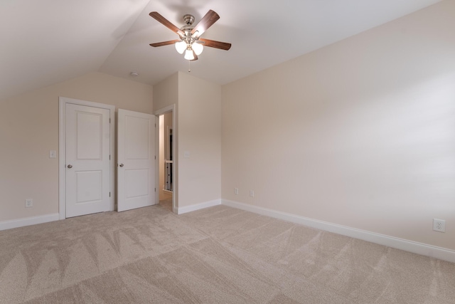 unfurnished bedroom with light carpet, lofted ceiling, baseboards, and a ceiling fan