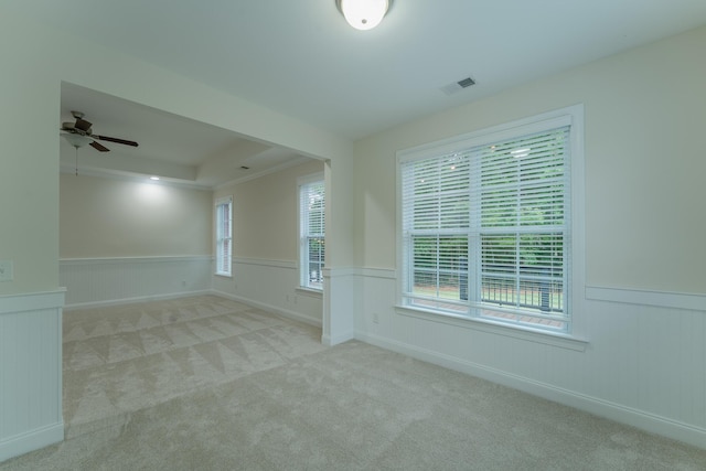 carpeted empty room featuring wainscoting, a ceiling fan, and a tray ceiling