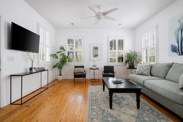 living room featuring ceiling fan, wood-type flooring, and a healthy amount of sunlight