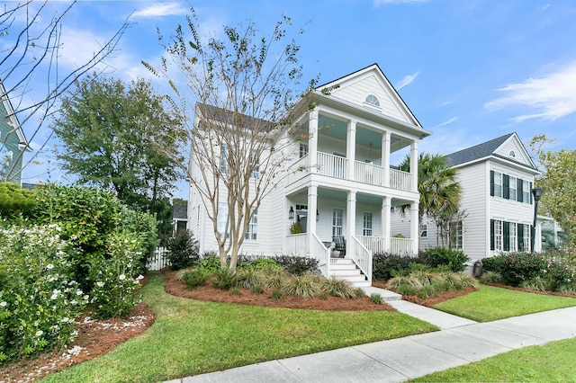 greek revival inspired property with a balcony, a front yard, and covered porch