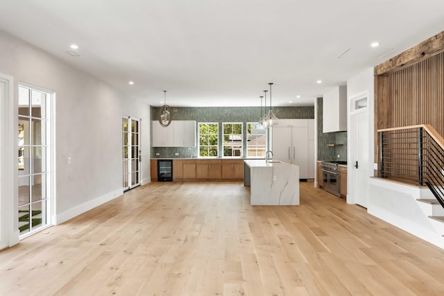 kitchen with wine cooler, backsplash, light wood-type flooring, recessed lighting, and light countertops