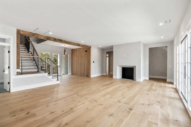 unfurnished living room with light wood-style floors, recessed lighting, baseboards, and stairs